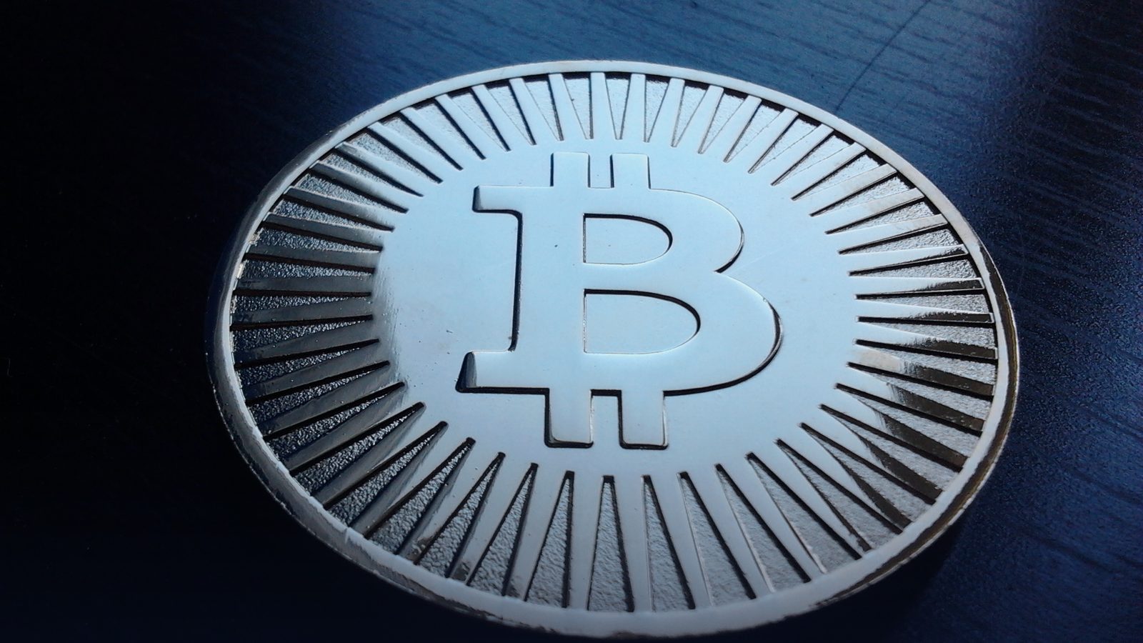 A brass novelty bitcoin coin on a dark surface