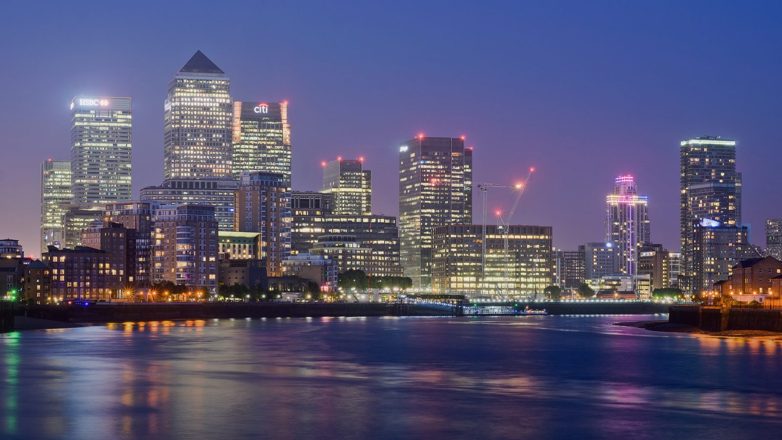 Canary Wharf's towers lit up at night over the Thames