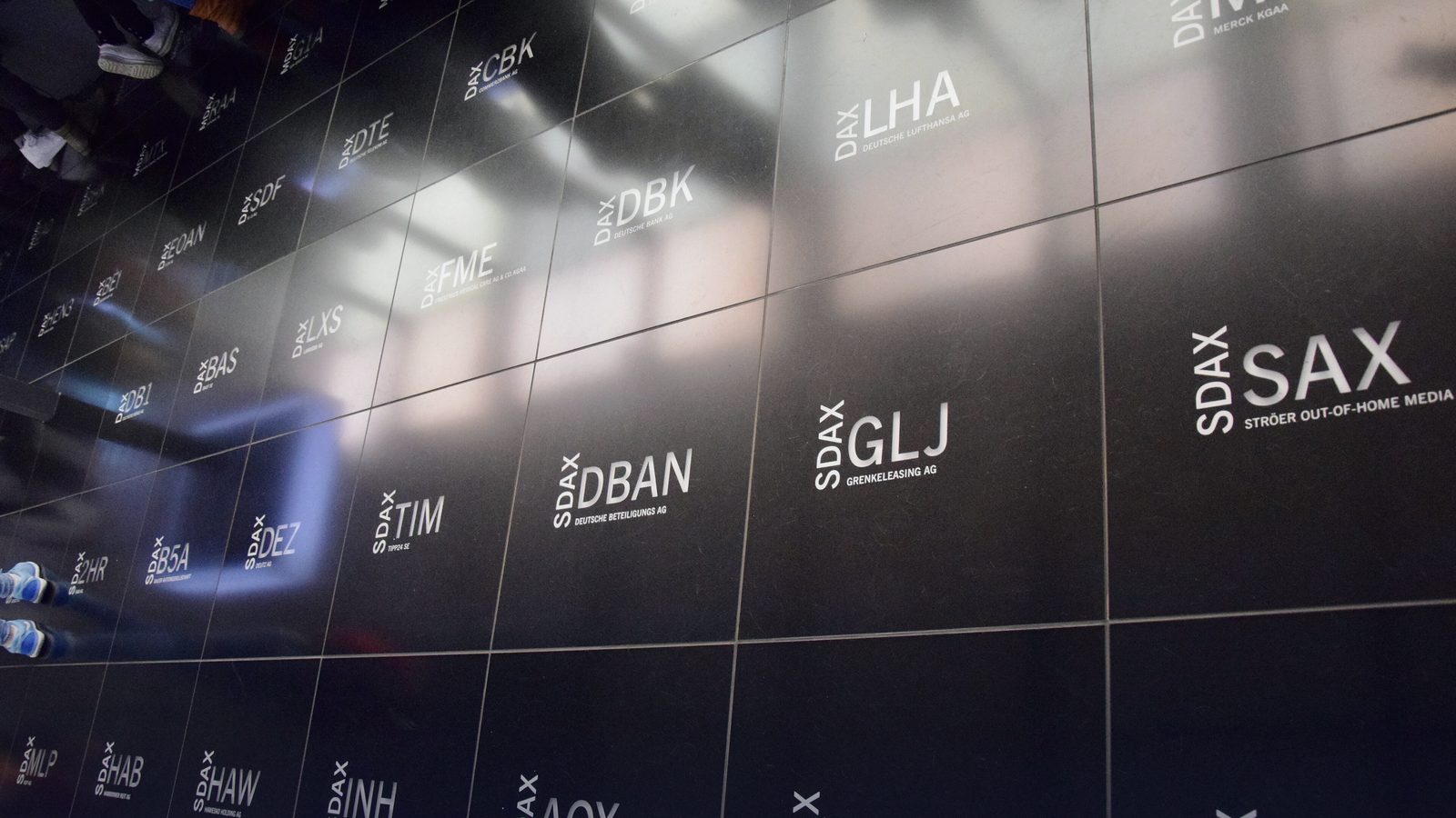 A dark wall of illuminated stock ticker symbols at an exchange